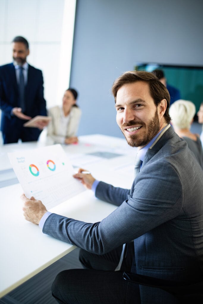 Man holding document with graphs in hand in a meeting