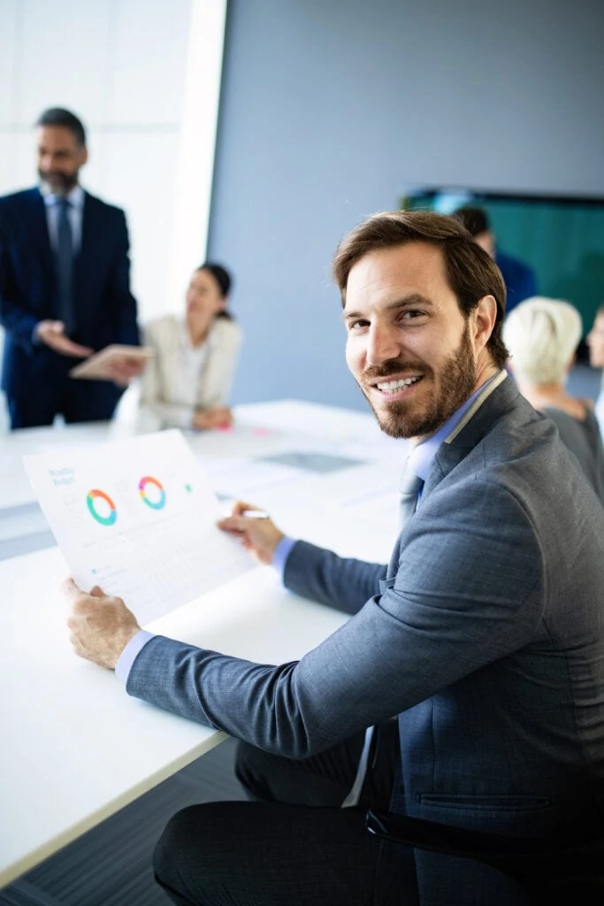 Man holding document with graphs in hand in a meeting