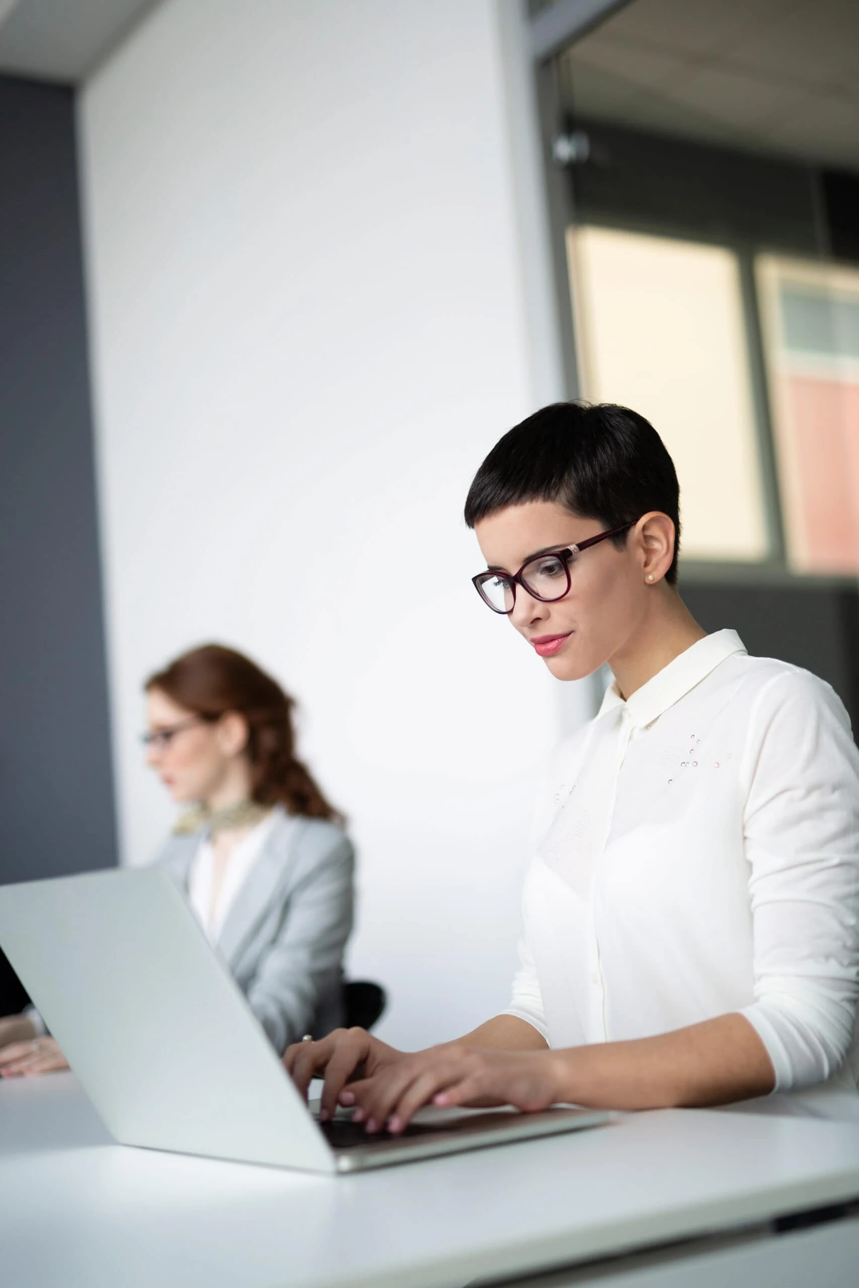 Frau macht Notizen am Laptop während eines Meetings