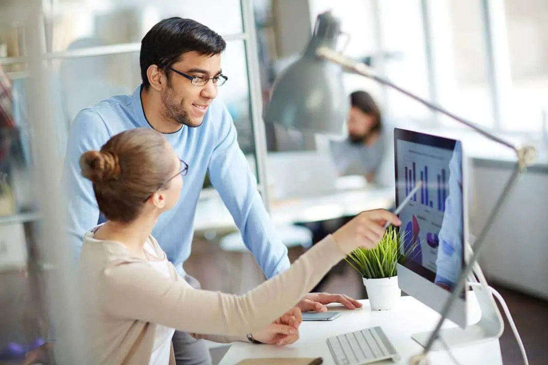 Work colleagues look at graphs together on the screen